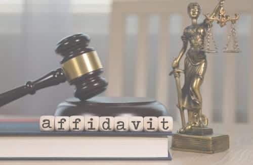 A book with the word Affidavit atop with a gavel and the scales of justice in the background.