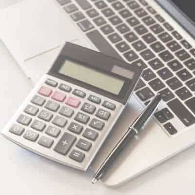 Calculator on a laptop keyboard with a pen beside.